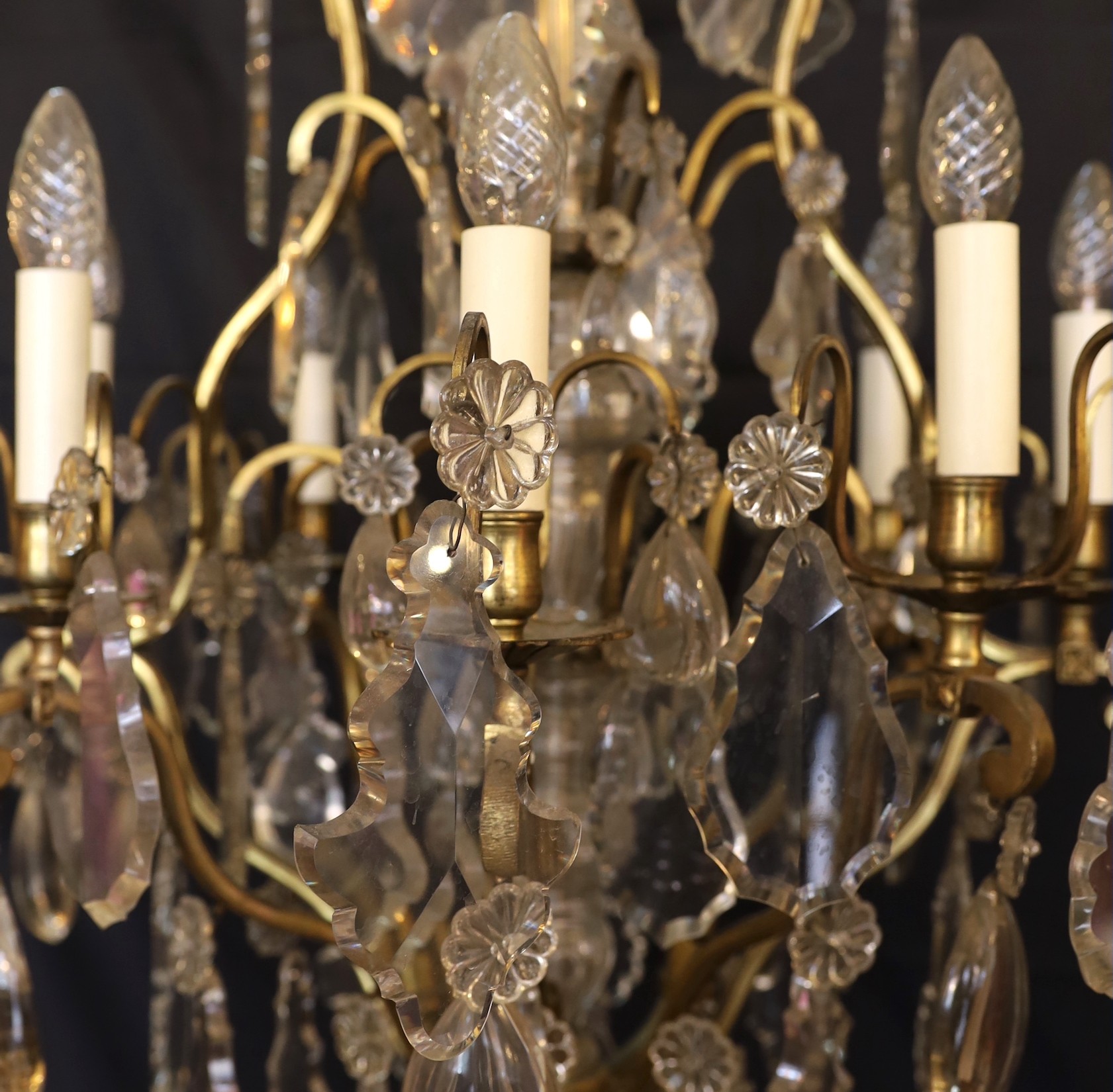 An early 20th century French bronze and cut glass twelve light chandelier, hung with tear, lozenge and flowerhead shaped drops, drop 114cm. width 72cm